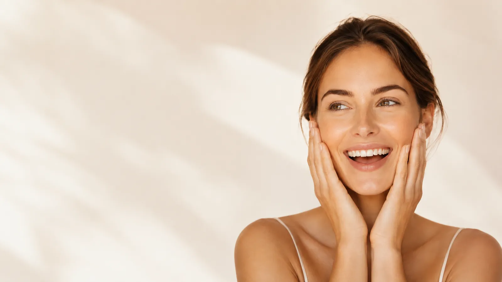 A smiling woman with clear, radiant skin cradles her face in her hands against a warm cream backdrop, illustrating the visible effect of the copper peptide serum.